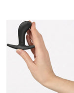 Dłoń trzymająca czarny silikonowy korek analny Fun Factory, prezentująca rozmiar i ergonomiczny kształt