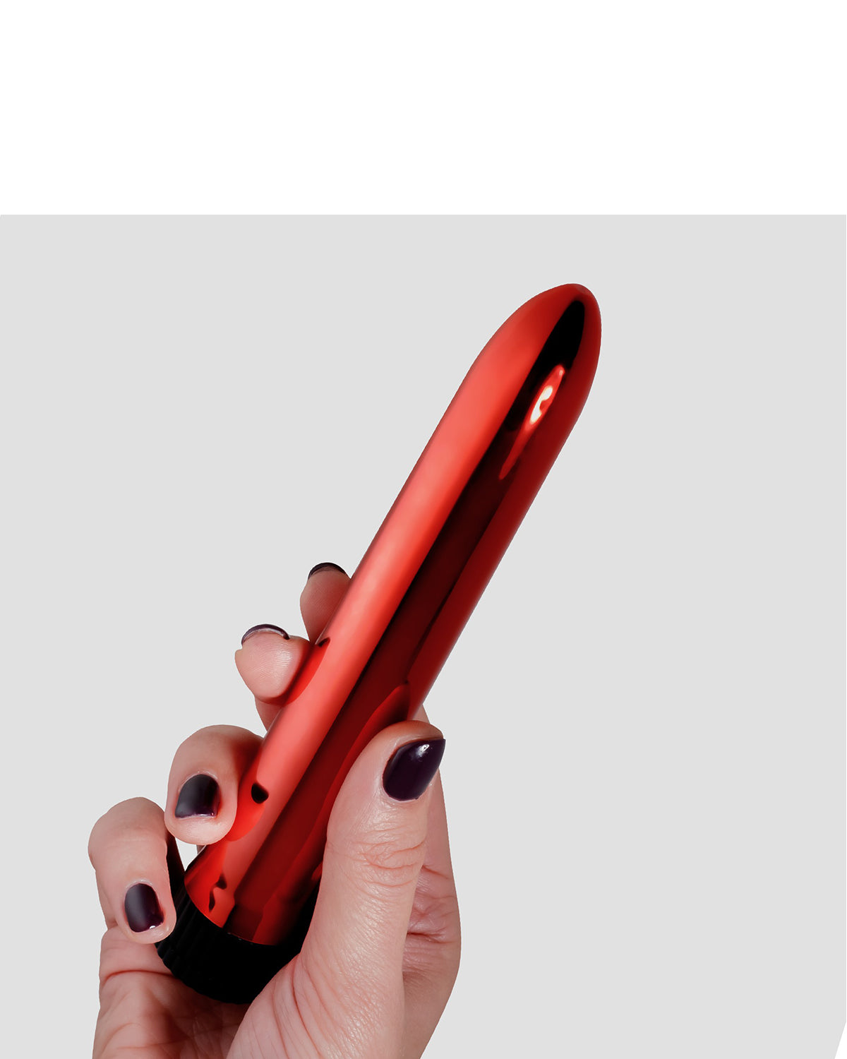 Czerwony błyszczący wibrator w dłoni z ciemnymi paznokciami na szarym tle z czarną podstawą