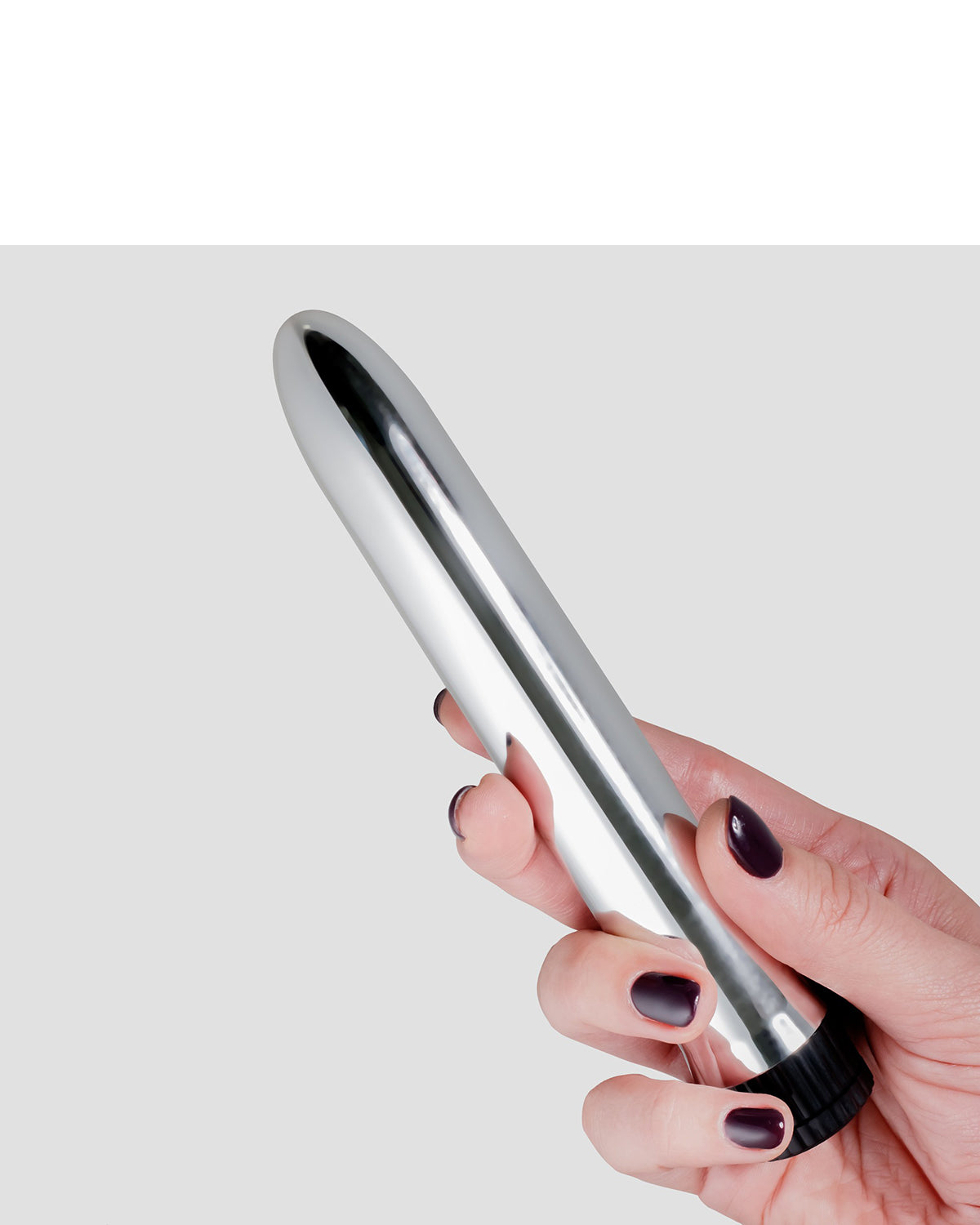 Dłoń trzymająca srebrny metaliczny wibrator, paznokcie pomalowane na ciemny kolor