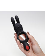 Dłonie trzymające czarny silikonowy pierścień z dwoma wypustkami i czerwonym przyciskiem kontrolnym