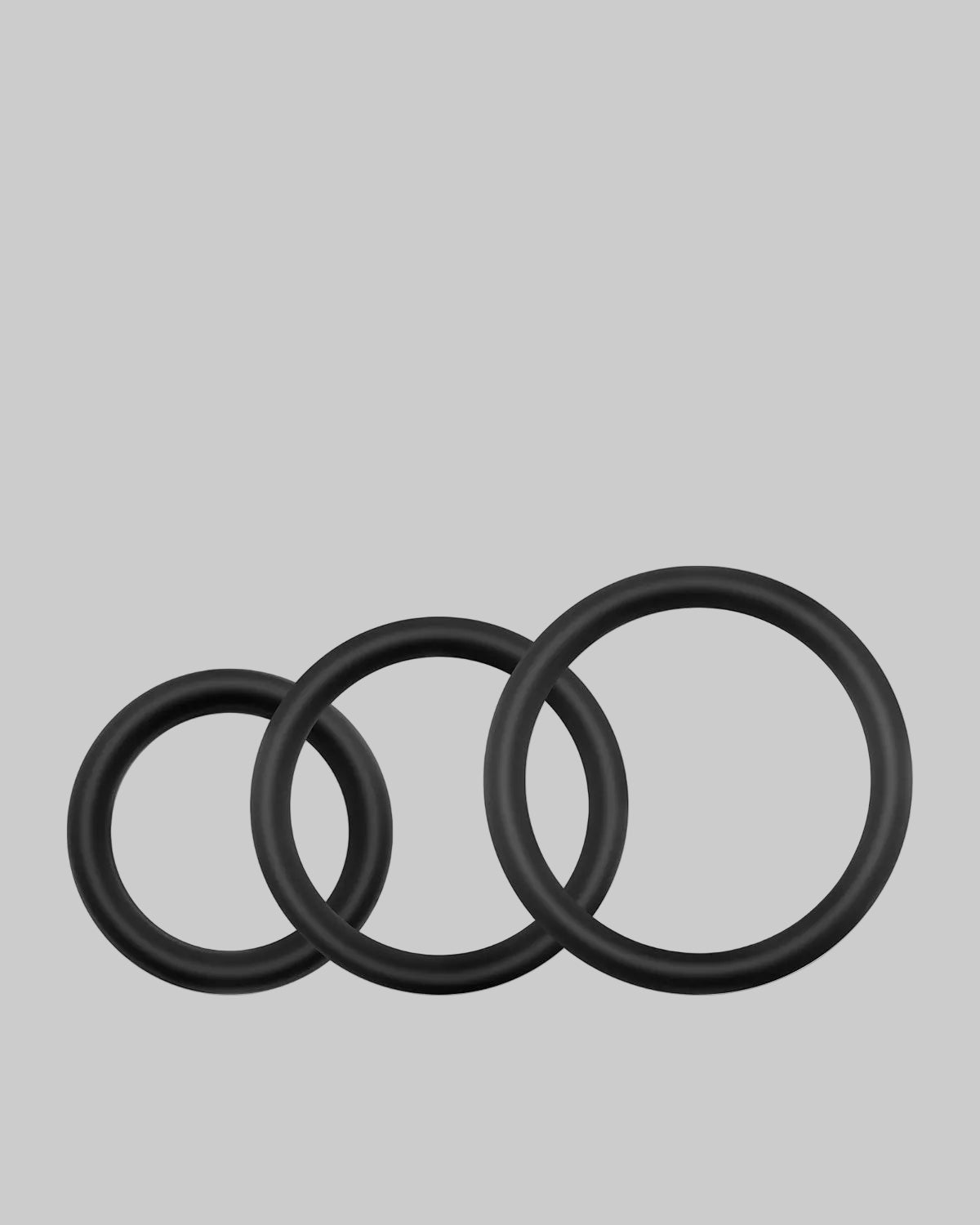 Trzy czarne silikonowe pierścienie o różnych rozmiarach ułożone obok siebie na białym tle